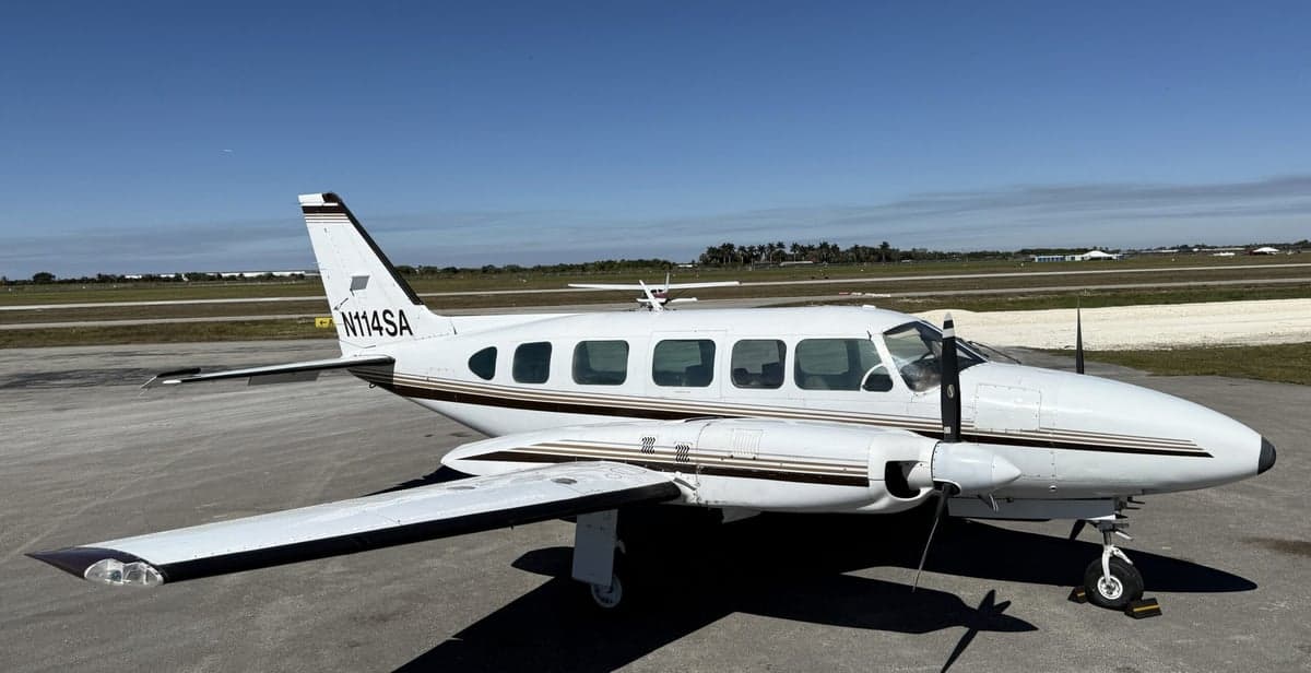 A white and brown twin-engine aircraft is parked on the tarmac.