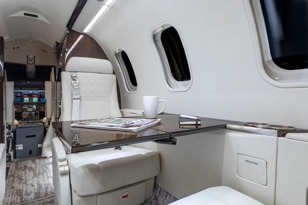 Interior view of the aircraft cabin with a table, seat, and magazine.