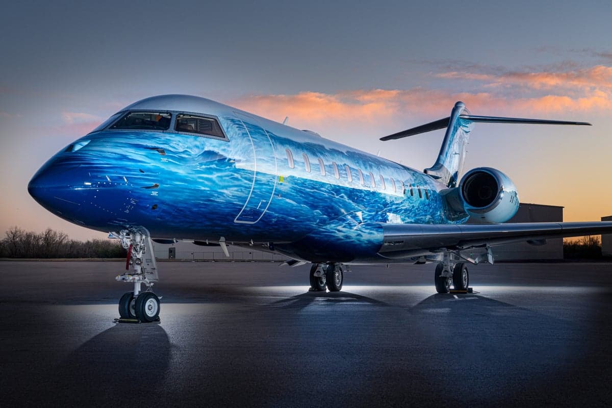 A private jet with a blue wave paint scheme parked on the tarmac.