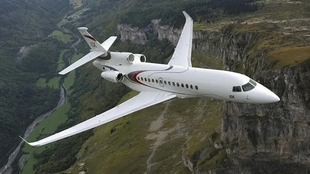 A Dassault Falcon 8X flying over a mountainous landscape.