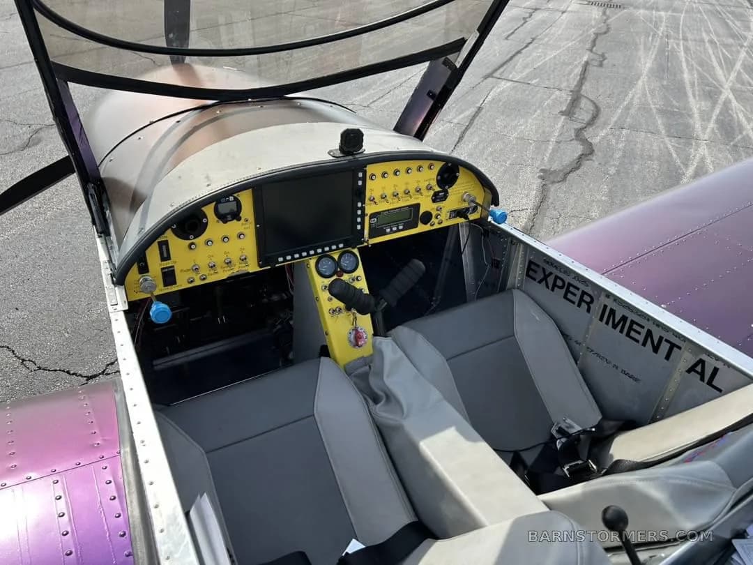 An overhead view into the open cockpit of a Zenith aircraft, showing the yellow instrument panel, controls, and grey seats.