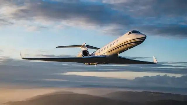 A Gulfstream business jet in flight against a cloudy sky.