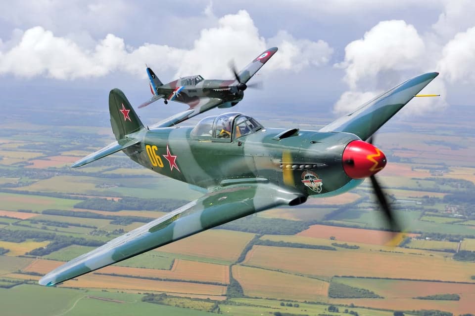Yak-3 in flight over a rural landscape.