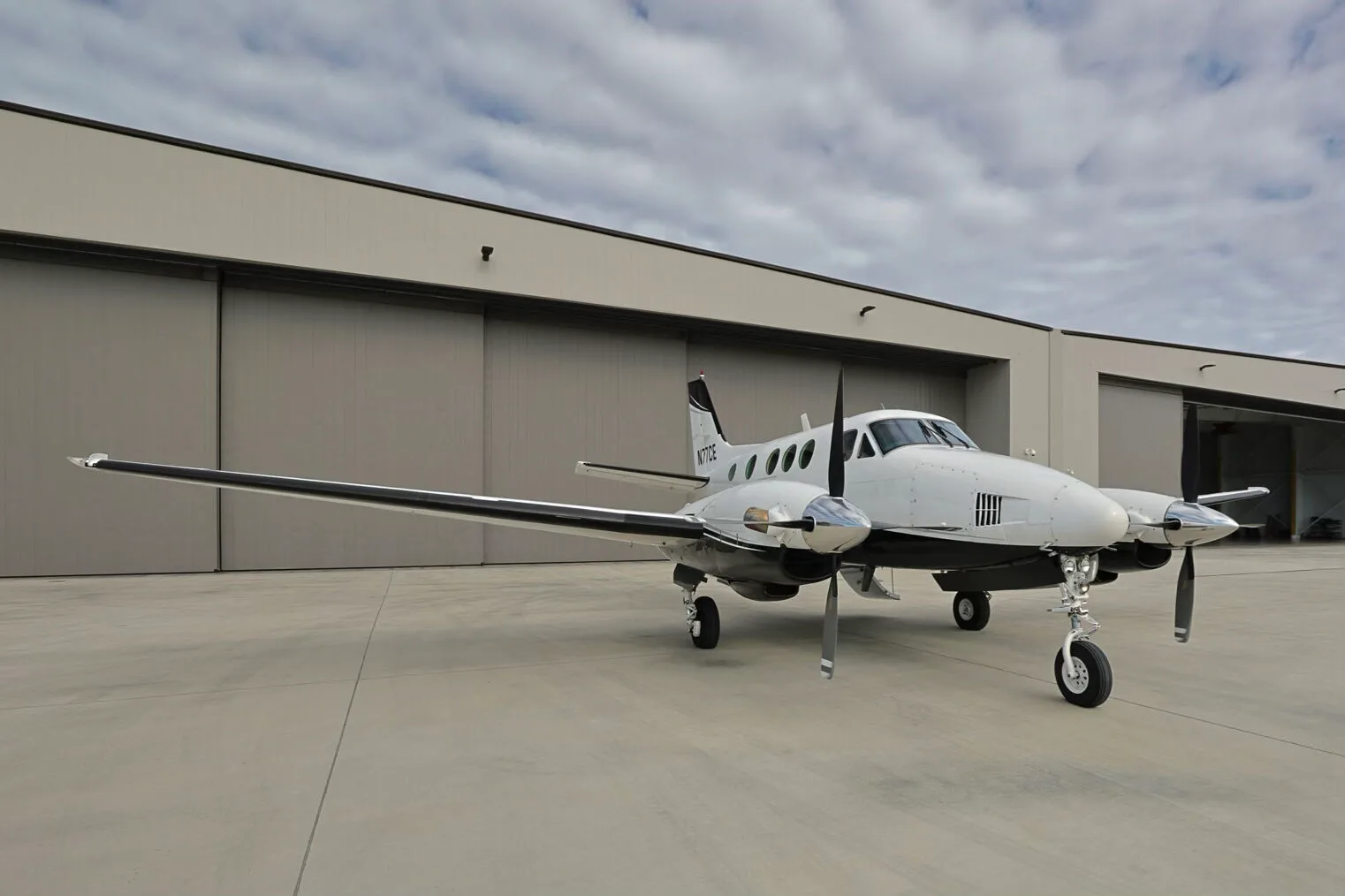 A front-left quarter view of the N77CE twin-engine turboprop aircraft parked on an airfield.