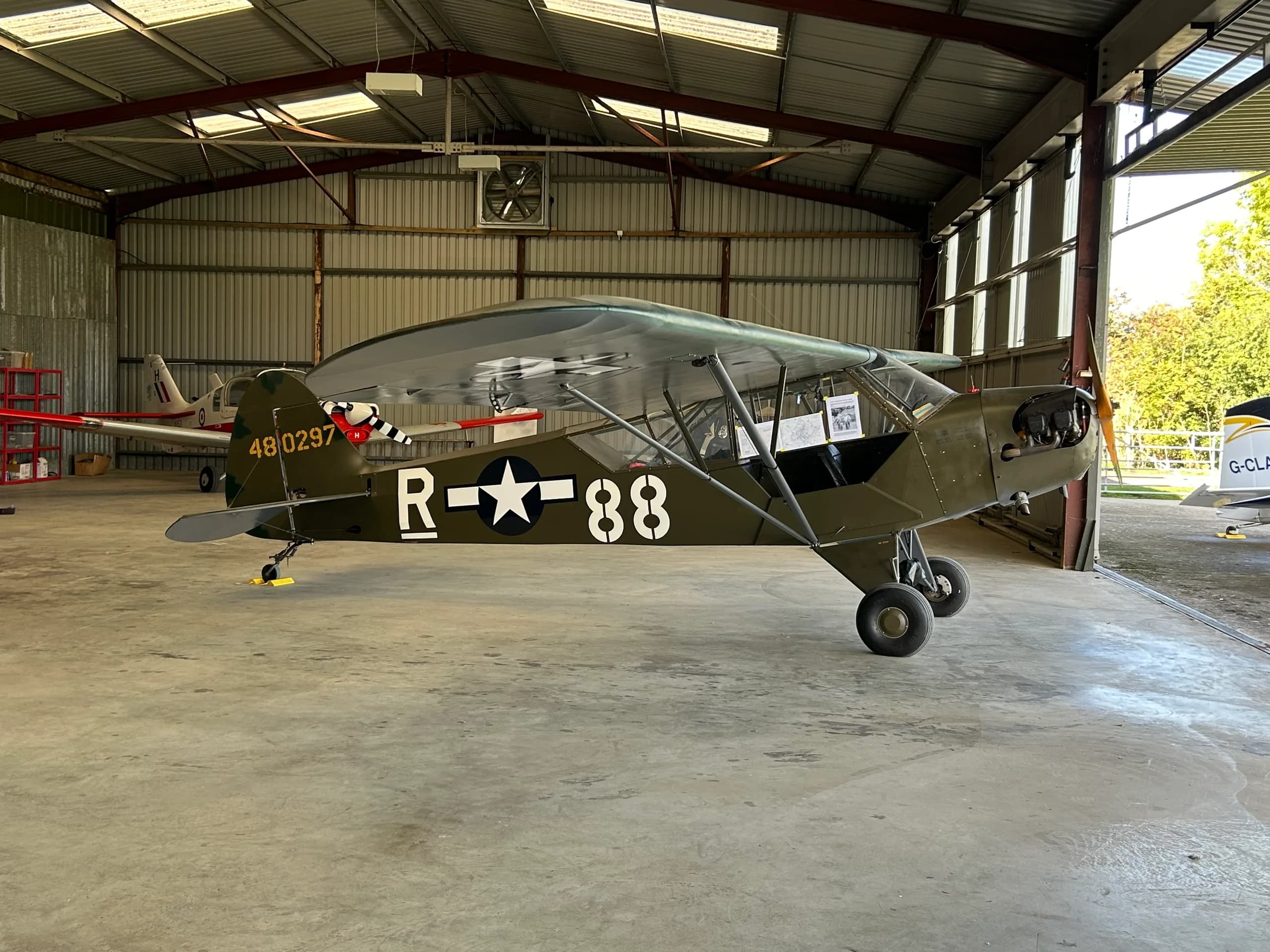 A vintage military aircraft with registration 48-0297 is parked inside a hangar.