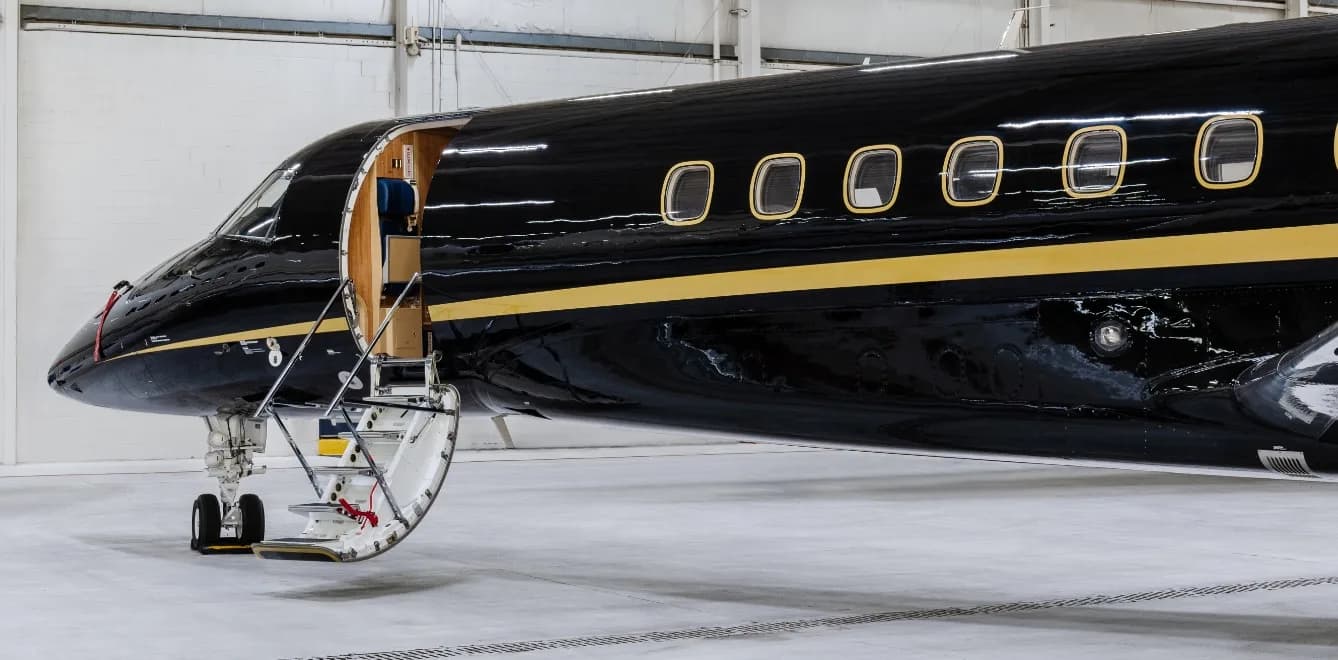Close-up of the front of the black and gold aircraft with the door open and stairs extended.