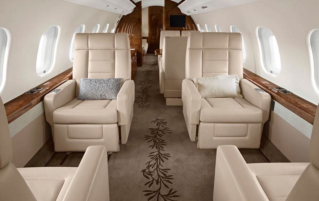 A view of the aircraft interior with four leather seats and wood trim.