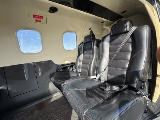 The interior of a TBM 930 aircraft with black leather seats.