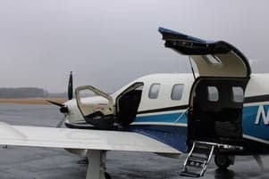 A TBM 930 aircraft with the door and hatch open on the tarmac.