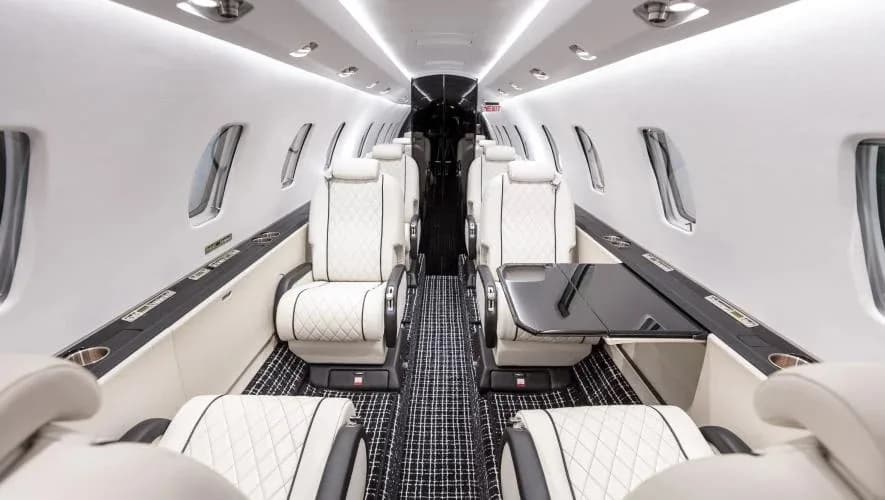 A view of the aircraft's interior with white leather seats and a black table.