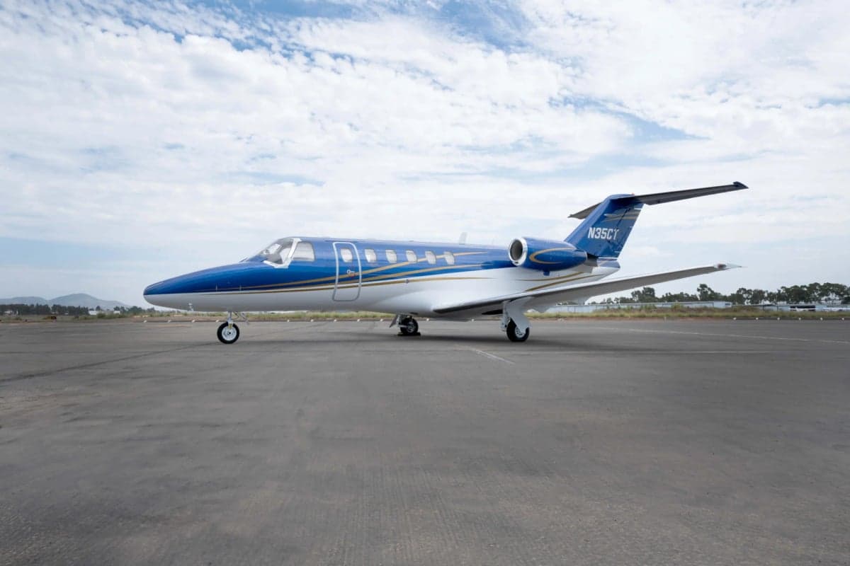 A Citation CJ2 aircraft with a blue and white paint scheme is parked on the tarmac.