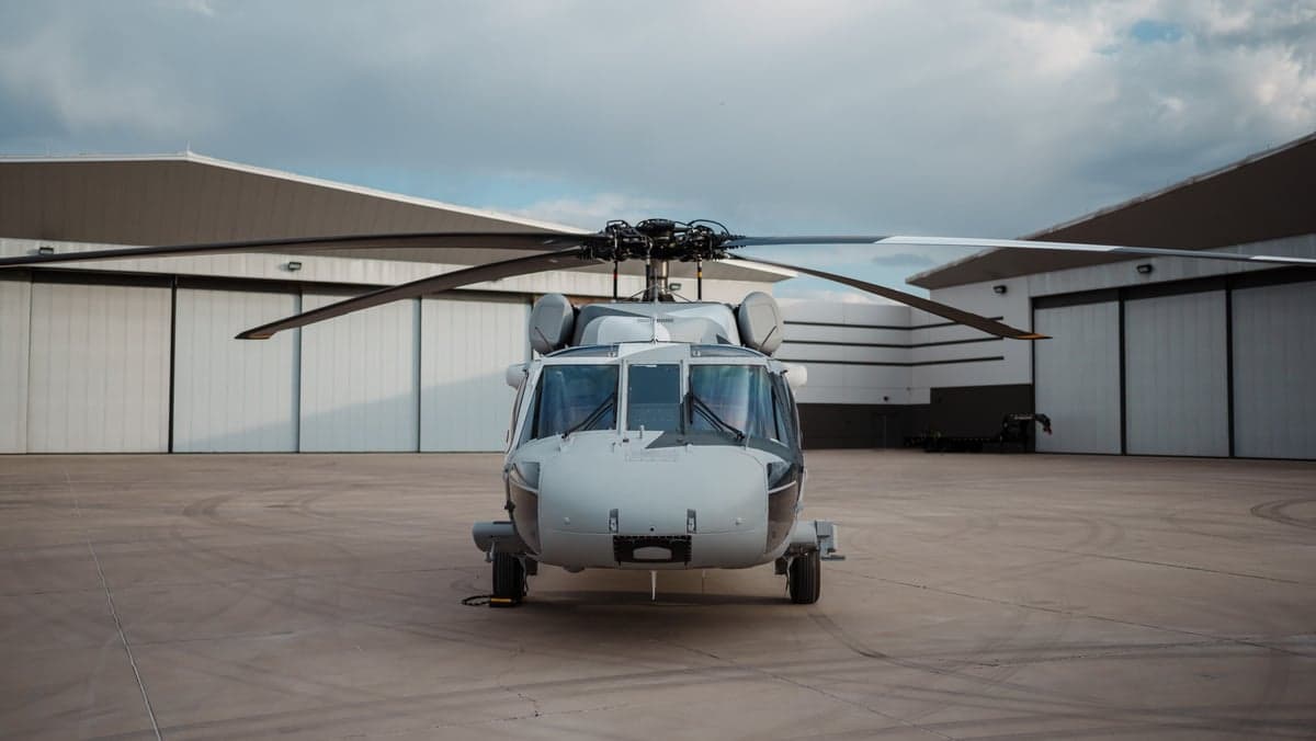 Front view of a Sikorsky S-70i helicopter with a gray camouflage paint scheme on the tarmac.