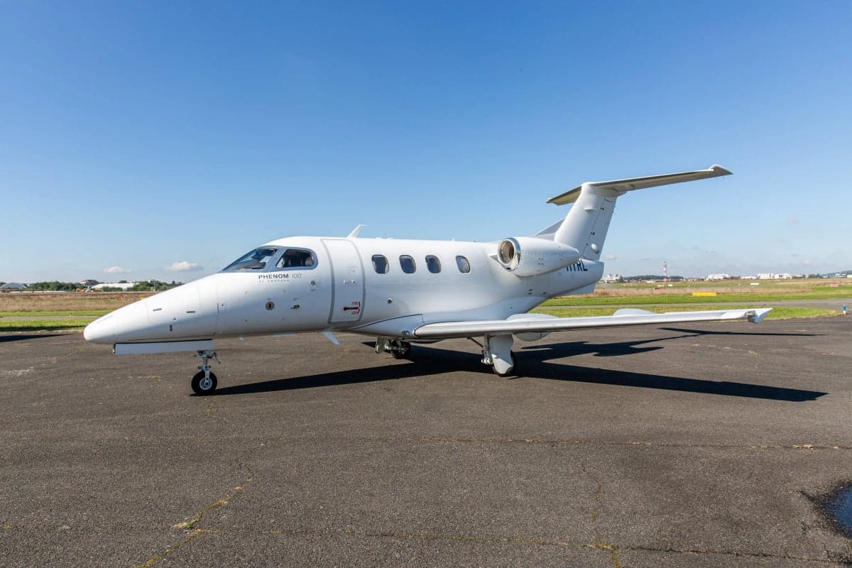 A white Embraer Phenom 100 (Phenom 100EV) with registration N11HL parked on a tarmac under a clear sky.