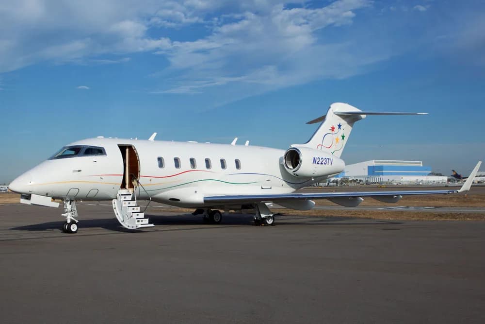 Side view of a white Bombardier Challenger with colorful stripes and tail number N223TV.