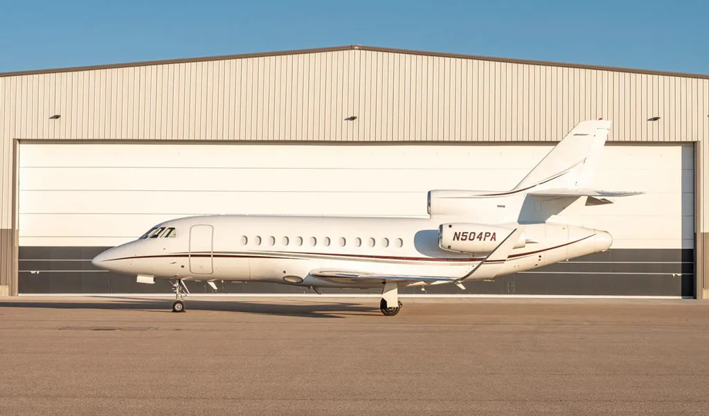 A Dassault Falcon 900EX business jet, registration N504PA, parked on the tarmac in front of a hangar.