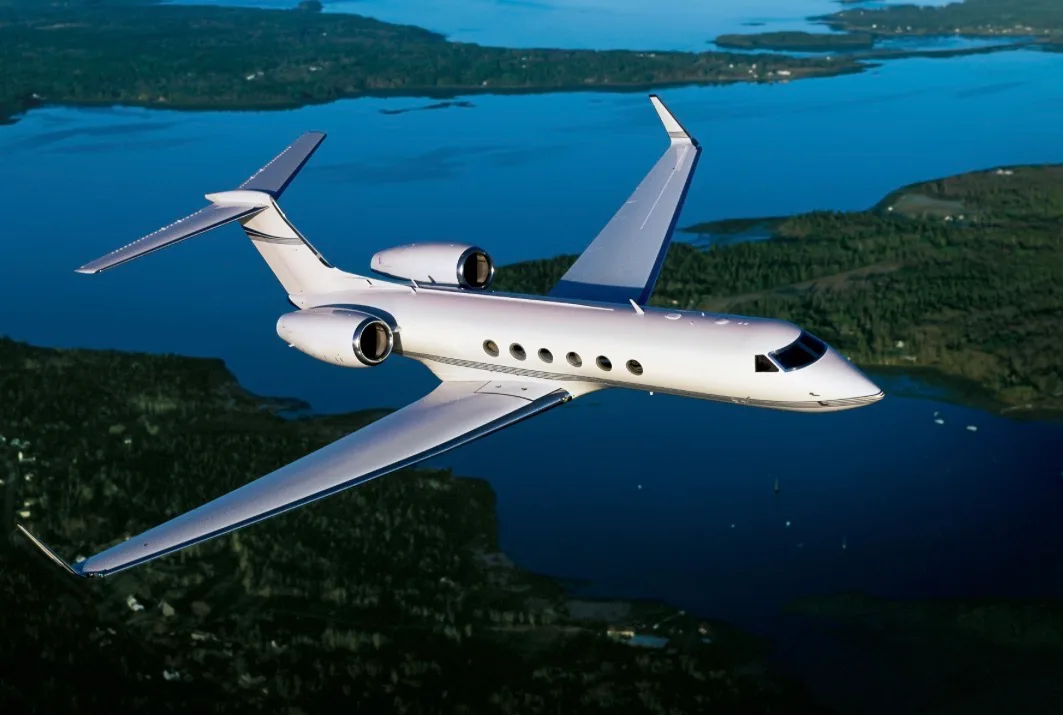 A Gulfstream jet in flight over a scenic landscape.