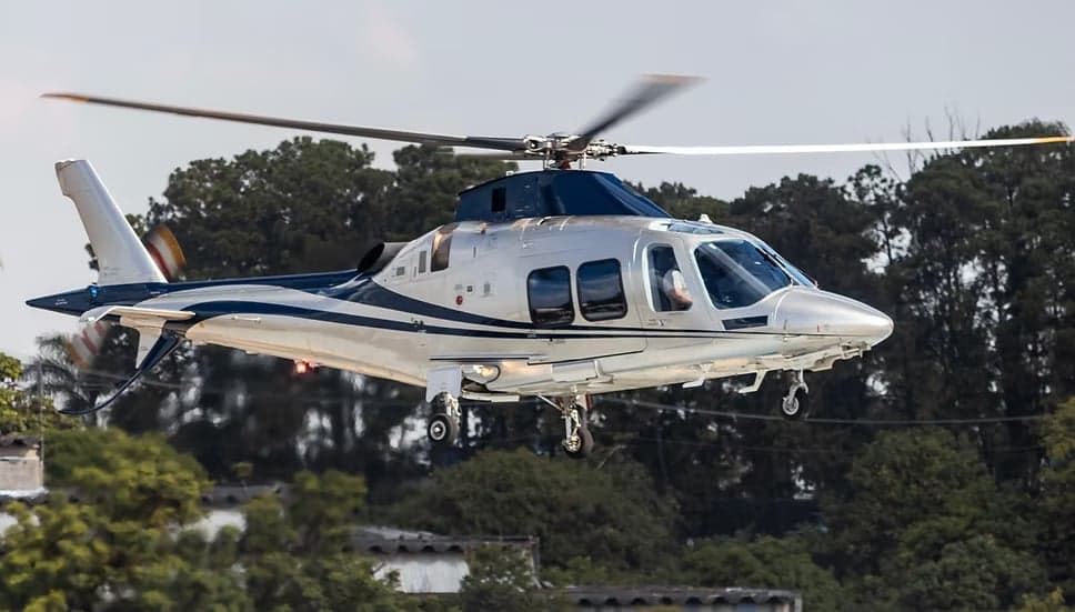 A silver and blue AgustaWestland AW109 helicopter in flight.