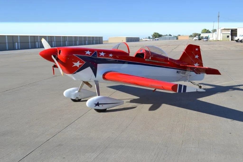 A red and white aircraft with stars on the tail and wings is parked on the tarmac.