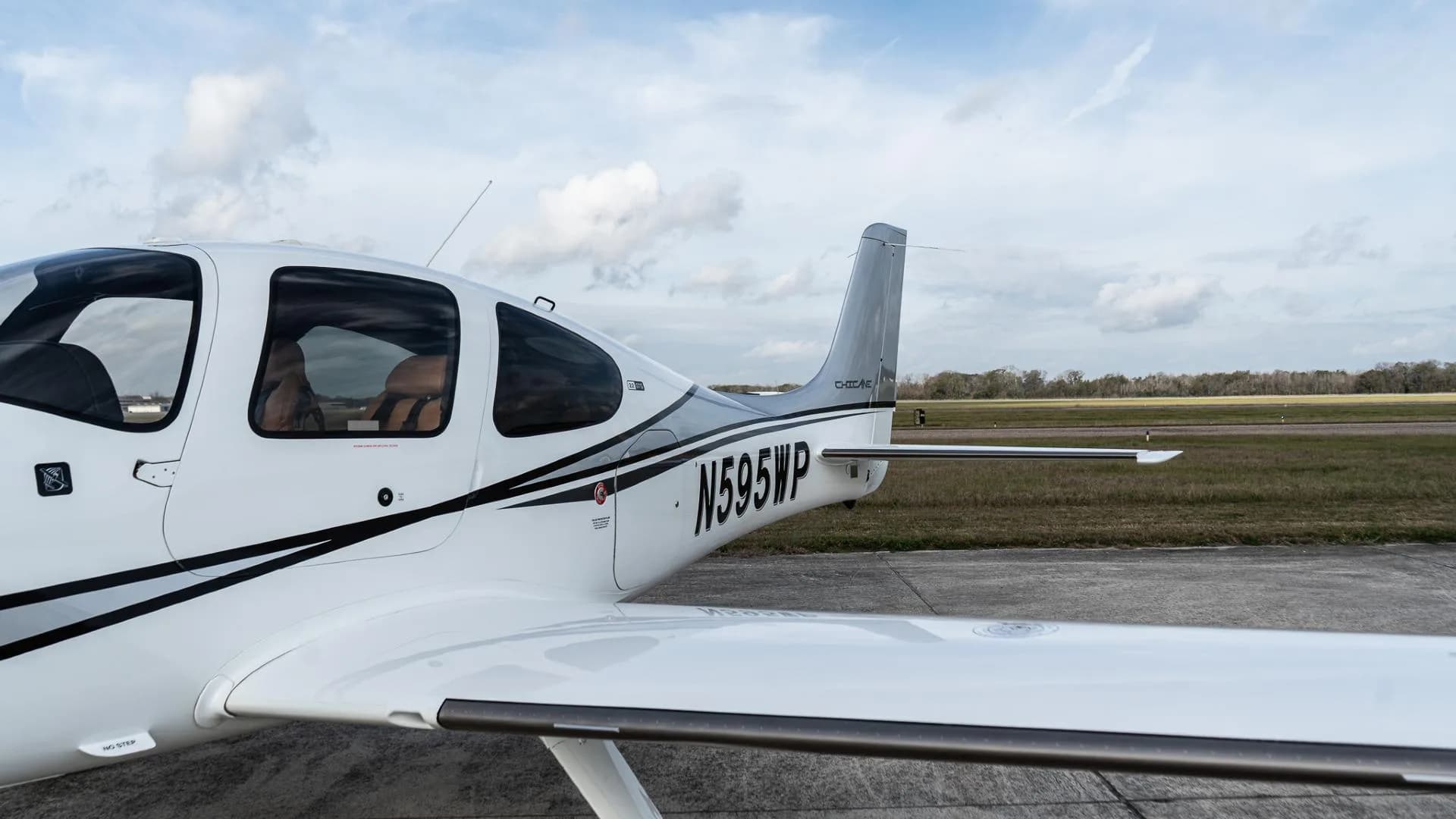Close-up side view of the tail and rear fuselage of a white Cirrus SR22, registration N595WP.