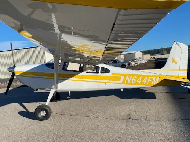 A side view of a white and yellow Cessna 172 aircraft with registration N644FM, showing the underside of the wing.