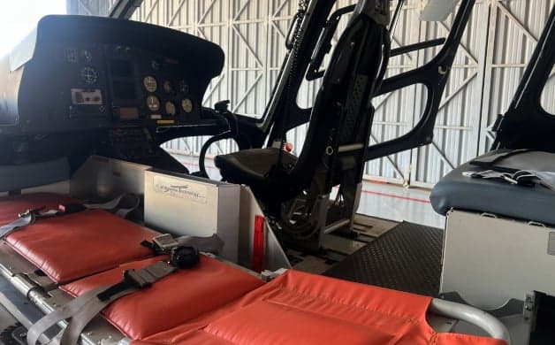 The helicopter's cockpit features a black instrument panel and controls.