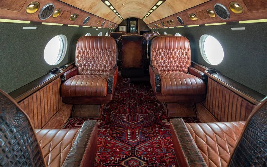 Aircraft interior with leather seats and a patterned rug.