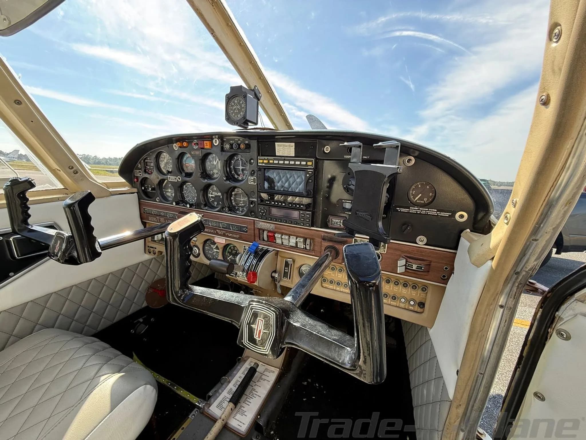 The cockpit of the Piper Arrow N3720T, showing the instrument panel, yokes, and quilted side panels.