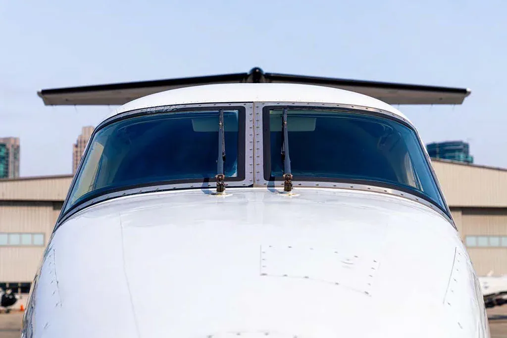 A head-on close-up view of the cockpit windshield of a white aircraft.