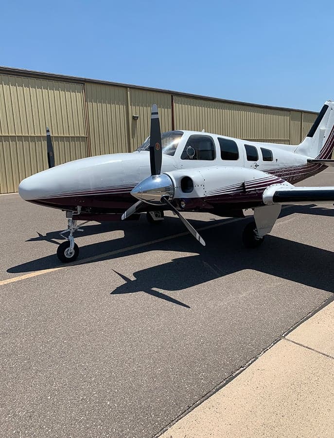 Front quarter view of the N3871C aircraft on the tarmac with a white and burgundy paint scheme.