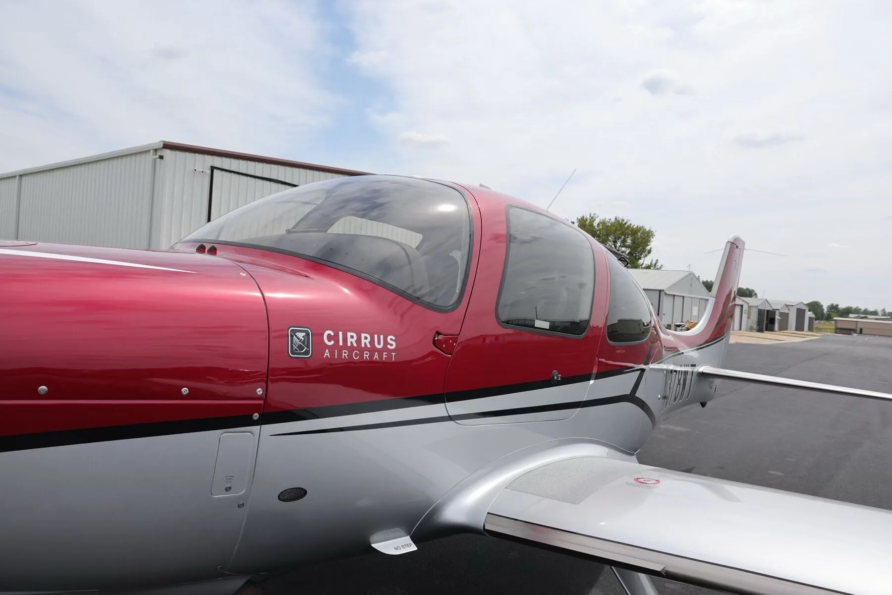 A close-up view of the red and silver fuselage and cockpit area of the Cirrus SR22T aircraft.