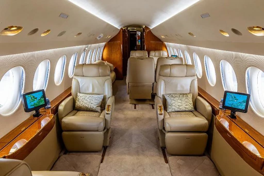 The luxurious interior cabin of a private jet with tan leather seats and wood accents.
