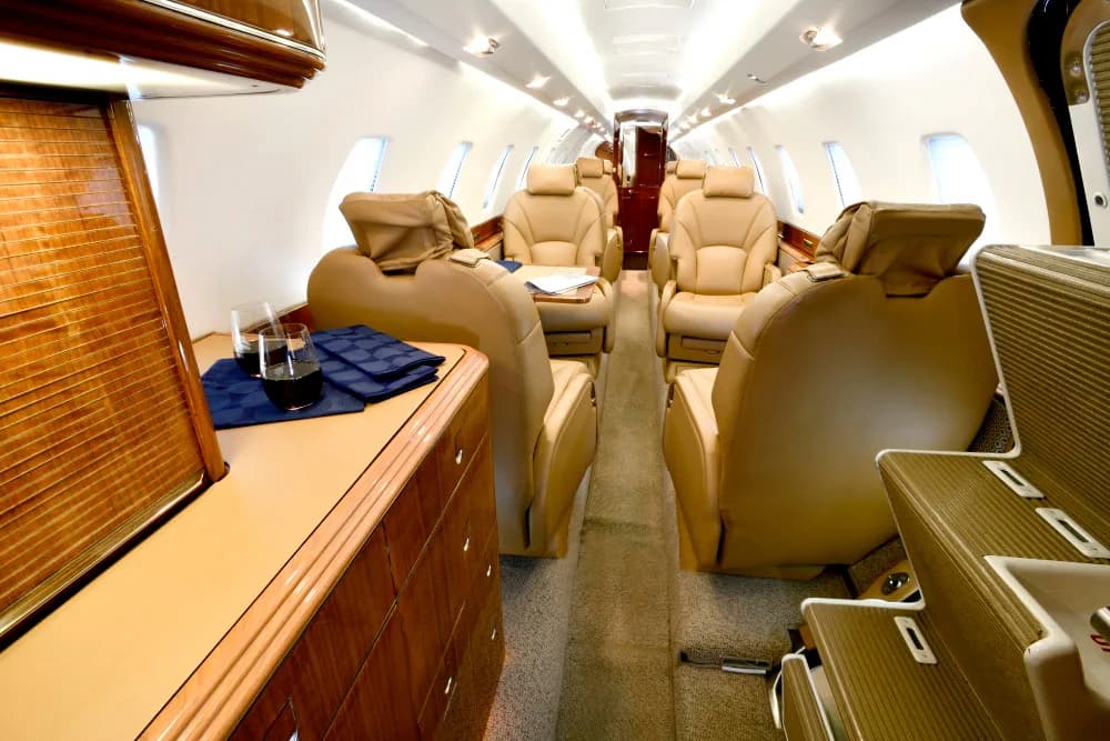 Aircraft interior with tan leather seats and wood trim.
