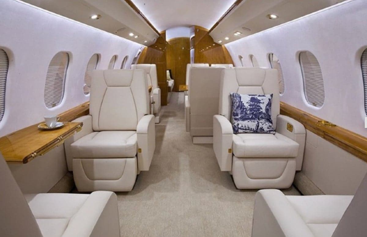 The interior of a private jet with cream-colored leather seats.
