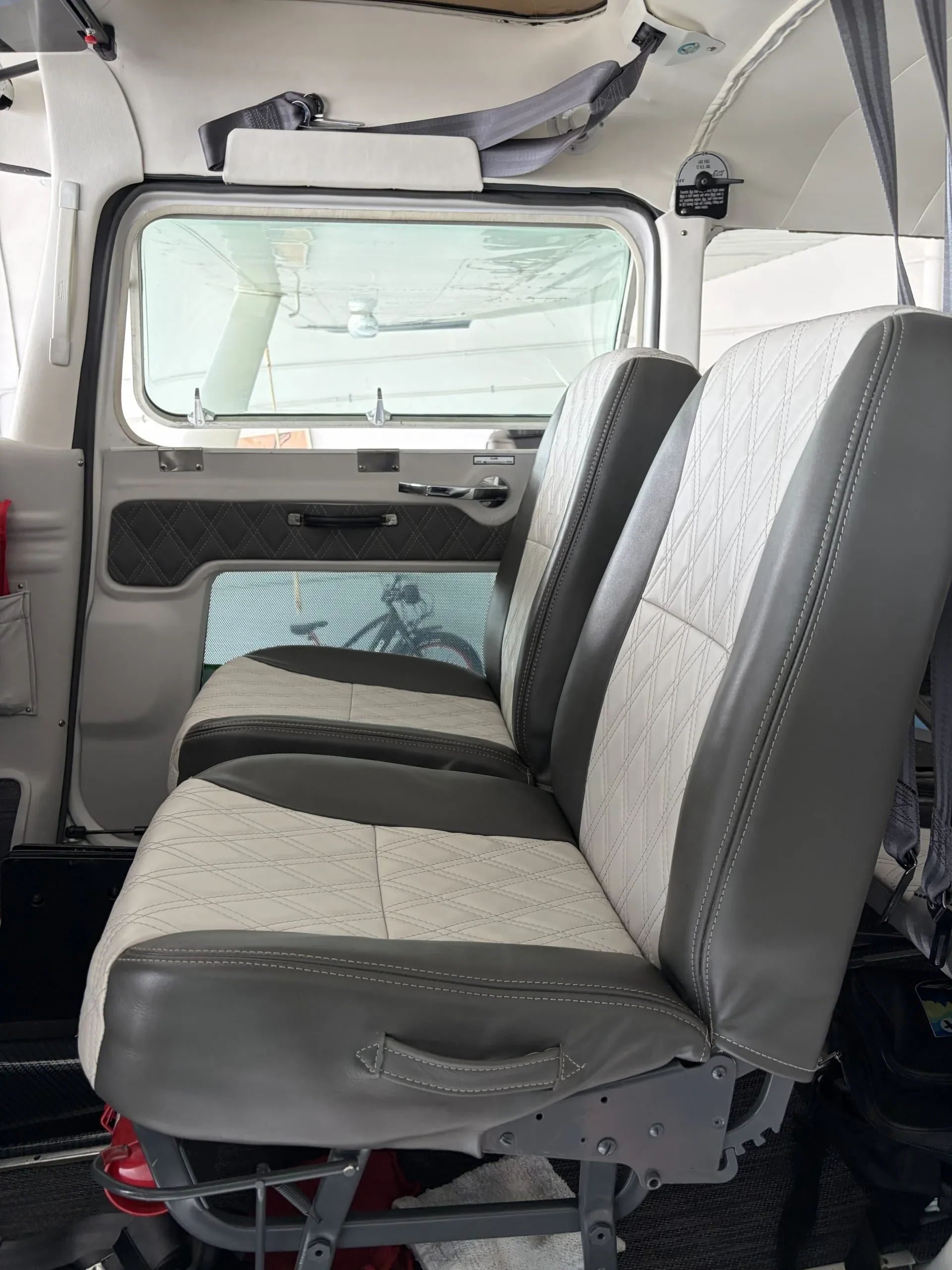 The aircraft's interior cabin with two-tone grey and white diamond-stitched seats.