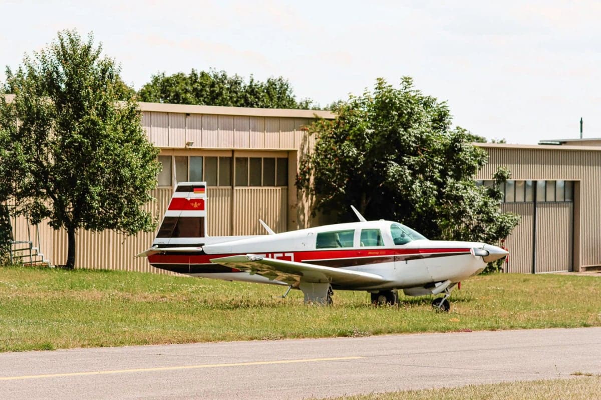 Mooney M20J aircraft parked in a hangar with other aircraft.