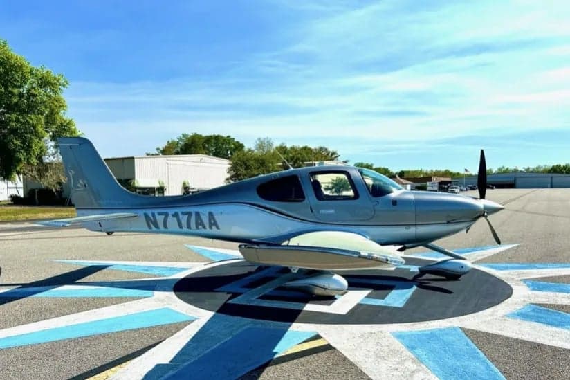 Side view of the silver Cirrus aircraft N717AA parked on the ramp.