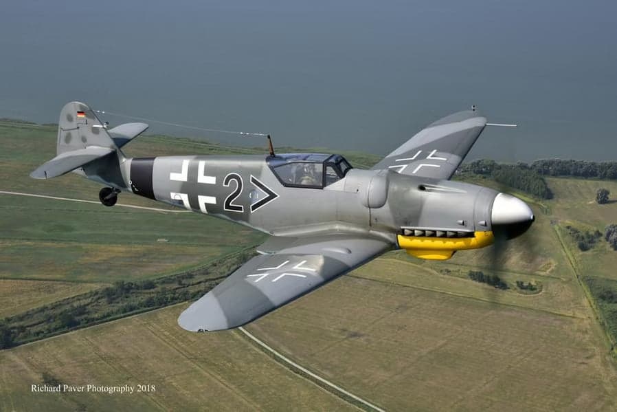 A Messerschmitt Bf 109 flying over a field.