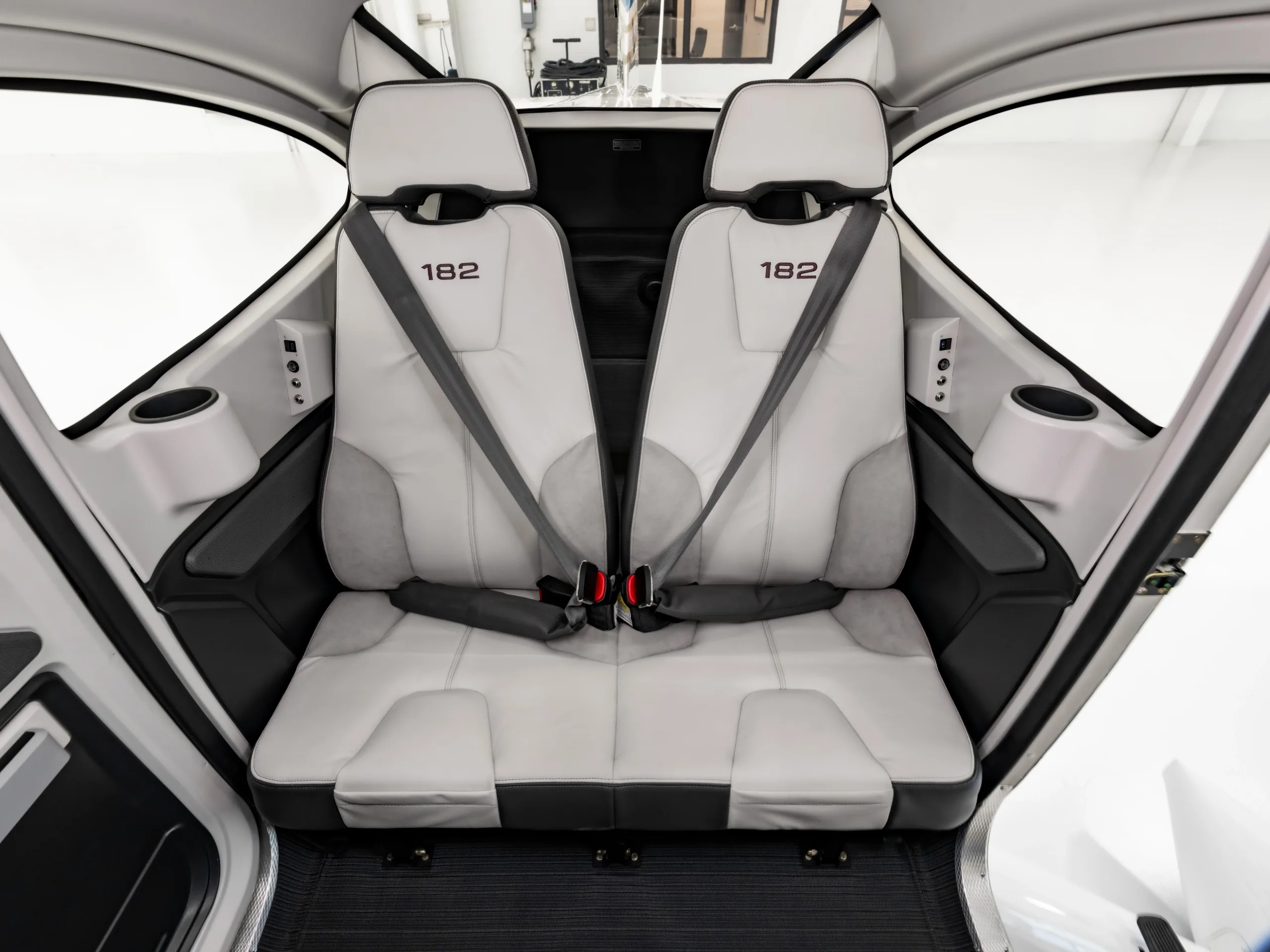 The light gray and dark gray rear seats of a Cessna 182 aircraft cabin are shown from above.