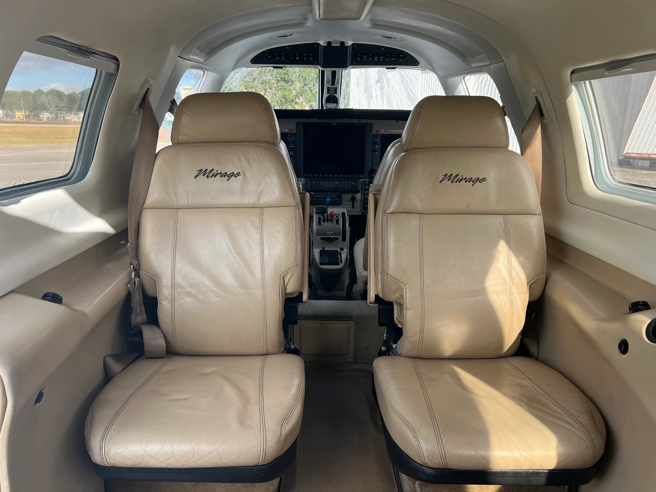 A view from the aircraft's beige leather cabin seats looking forward into the cockpit area.