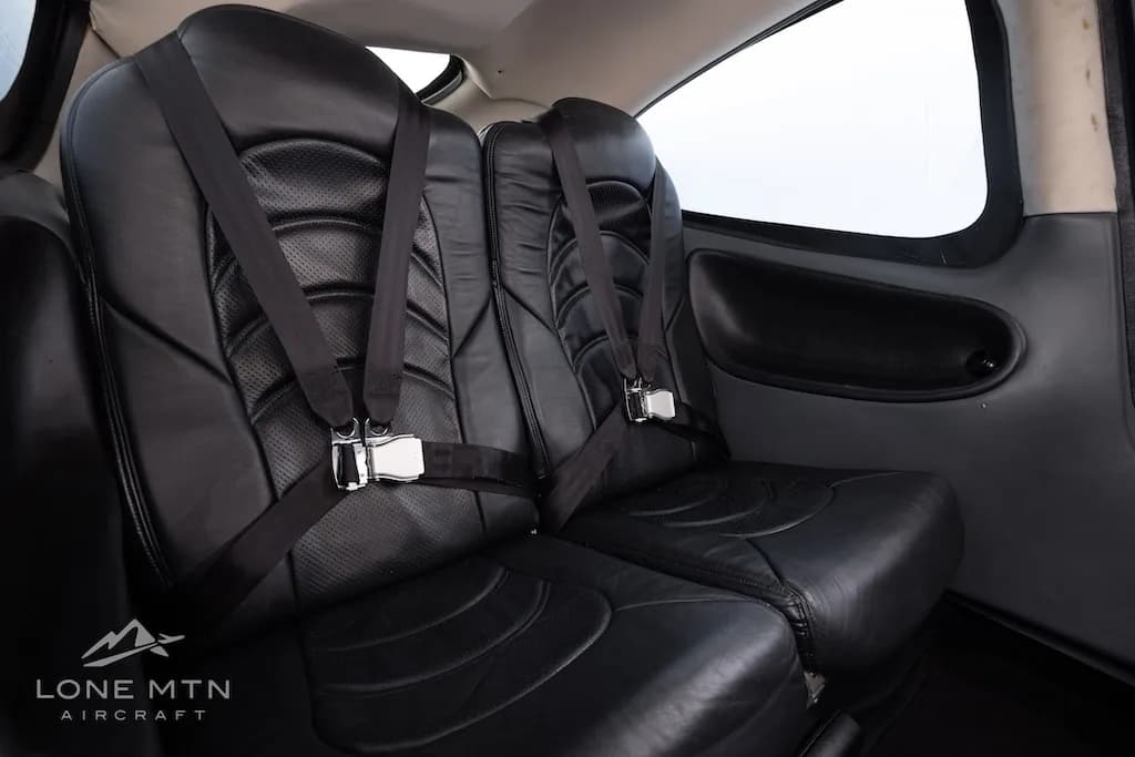 Side view of the black leather rear seats with seatbelts in the aircraft cabin.