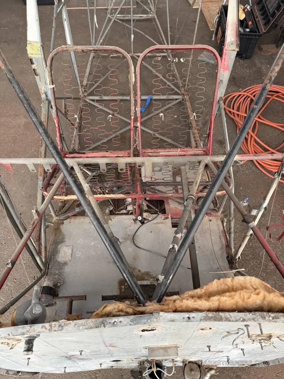 Overhead view of an aircraft fuselage frame showing exposed seat springs and internal structure.