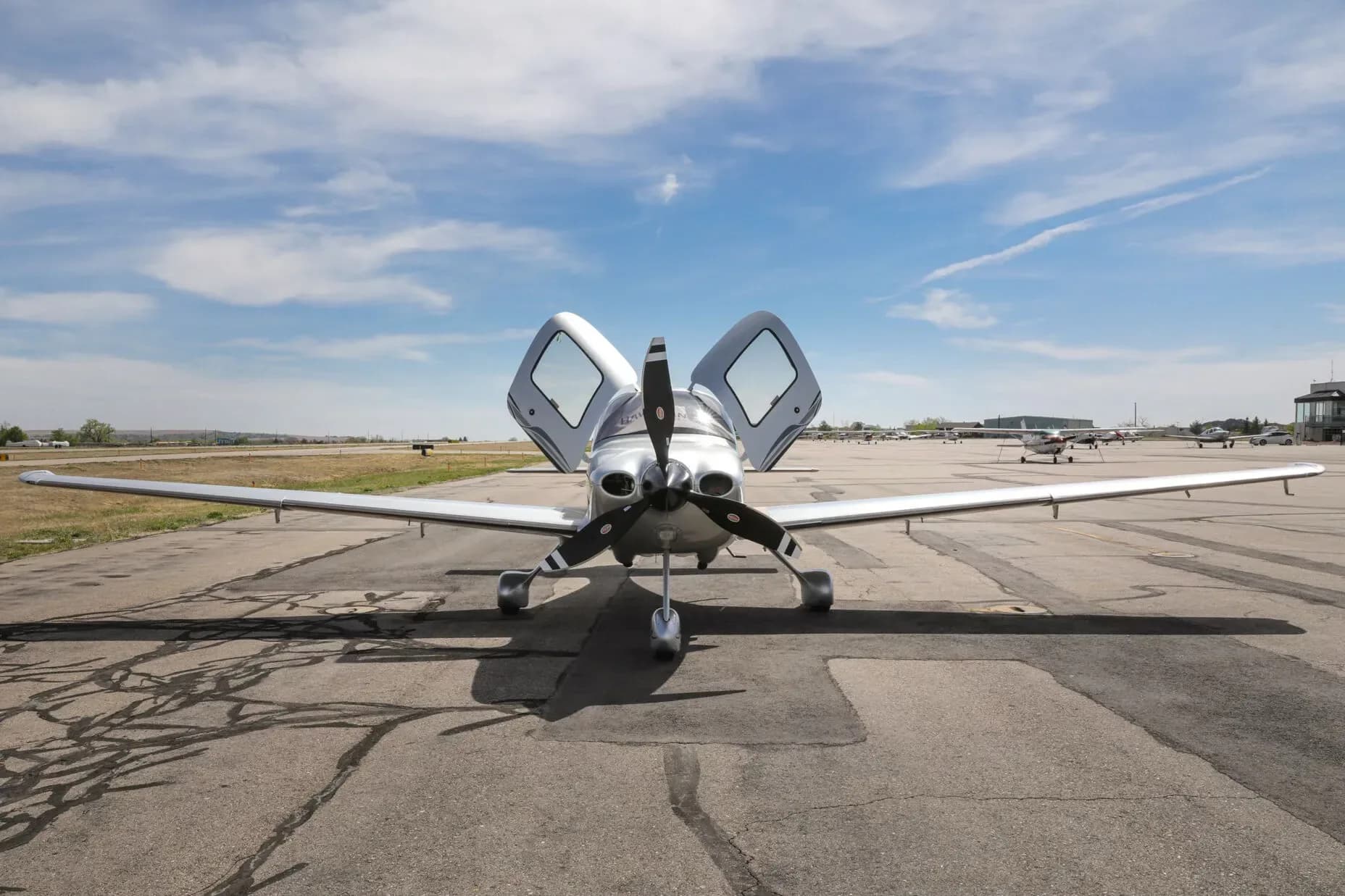 A silver Cirrus SR22T aircraft, registration N429SR, viewed from the front with both doors open, parked on an airfield.