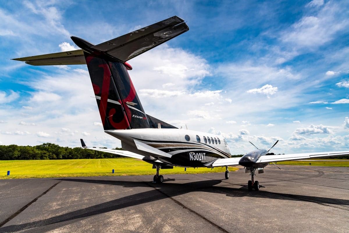 Rear view of a King Air aircraft parked on the tarmac with a distinctive tail design.
