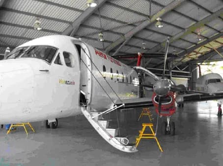 A white turboprop aircraft parked inside a hangar with the door open.