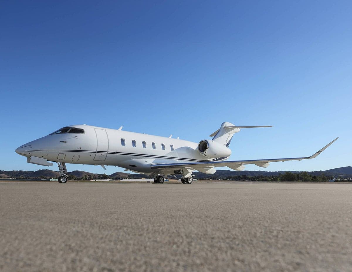 Side view of a white aircraft with blue accents parked on the tarmac.