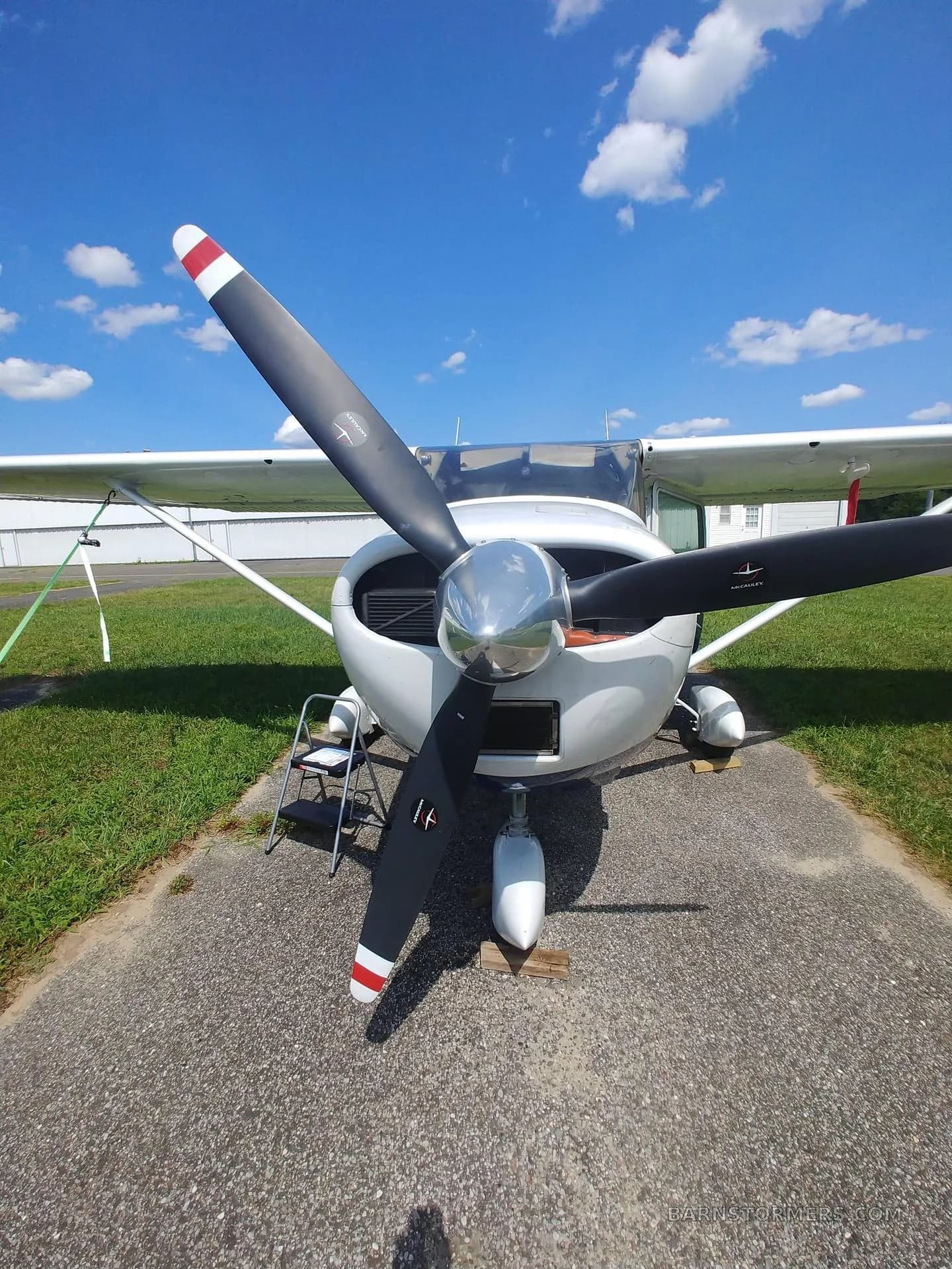 Front view of a white single-engine propeller aircraft (N274VF) with a polished spinner, parked on an asphalt path.