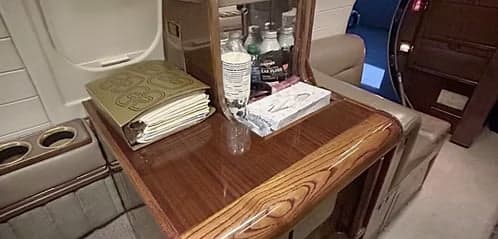A close-up of a wooden table and storage area inside the aircraft cabin.