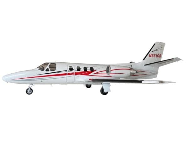 A white Cessna Citation jet with red and black stripes, registration N551GB, viewed from the side.