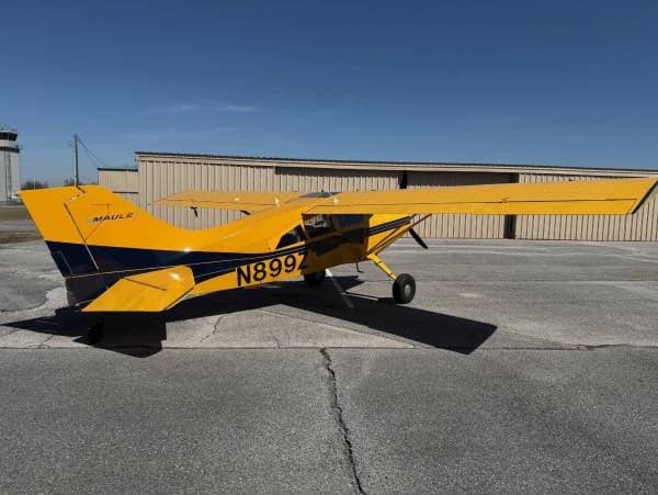 A yellow and blue Maule M-7-235 aircraft with registration N899Z parked on the tarmac.