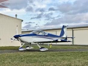 A blue and white aircraft is parked on the ground near a building.